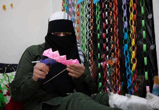 At home in Atarib, western Aleppo countryside, northwestern Syria Huda*, 25, places the petals made from pink ribbons in a row and glues them together using glue to start forming a flower.
